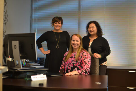 three happy working women behind desk